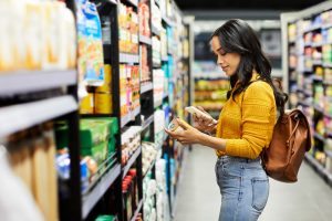 Femme qui regarde un produit dans un supermarché.